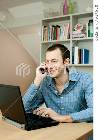 Young man using laptop and phone Young man using laptop and phone 7914530