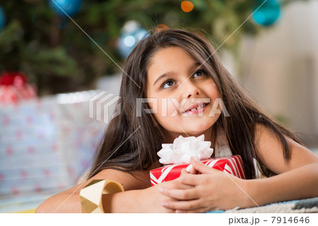 Girl holding Christmas present on floor Girl holding Christmas present on floor 7914646