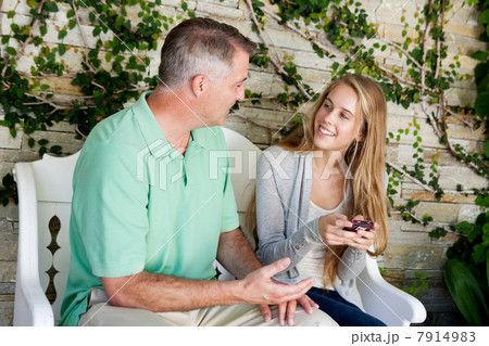 Mature man and daughter sitting together outside 7914983