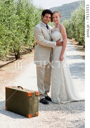 Newlyweds on country road with suitcase 7915053