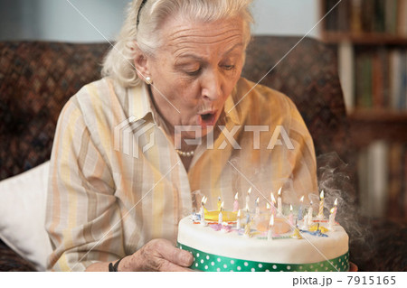 Senior woman blowing out birthday candles 7915165