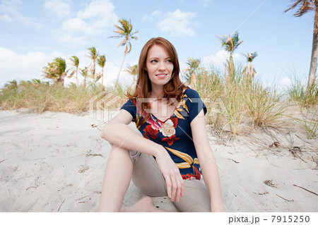 Young woman sitting on beach, portrait Young woman sitting on beach, portrait 7915250