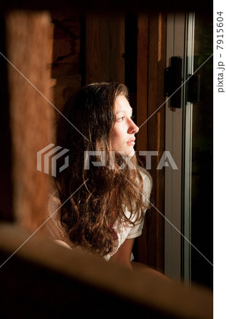 Teenage girl staring out of an open window Teenage girl staring out of an open window 7915604