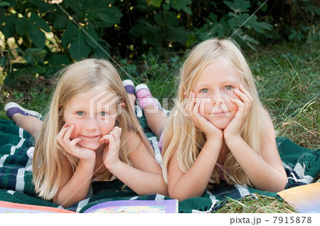 Two girls lying on blanket with books Two girls lying on blanket with books 7915878