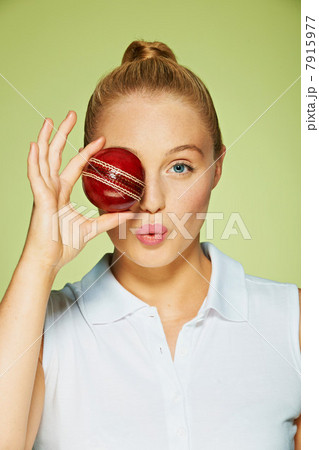 Young woman holding cricket ball over her eye Young woman holding cricket ball over her eye 7915977