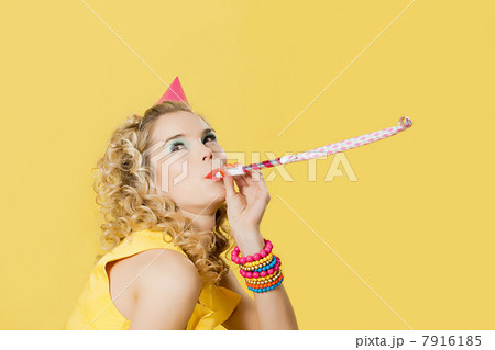 Young woman wearing party hat with party blower 7916185