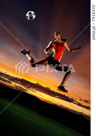 Female footballer in mid air against sunset Female footballer in mid air against sunset 7916335