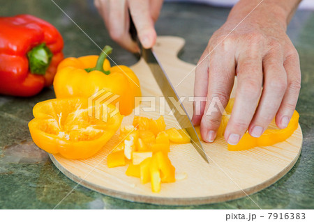 Woman chopping peppers on chopping board 7916383