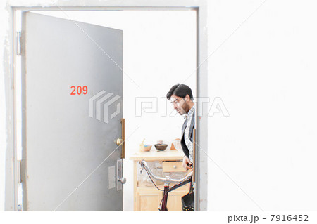 Man wheeling bicycle out apartment door 7916452