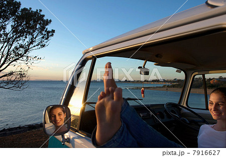 Young woman with feet up on camper van window 7916627