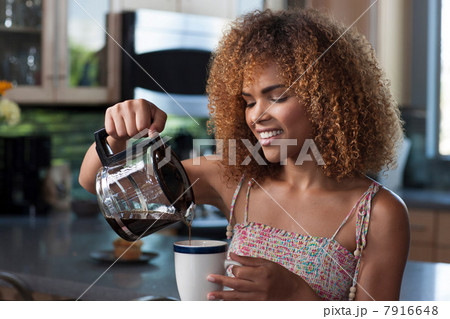 Mid adult woman pouring coffee from pot, smiling Mid adult woman pouring coffee from pot, smiling 7916648