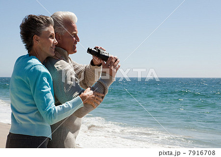 Mature couple at the beach with binoculars Mature couple at the beach with binoculars 7916708