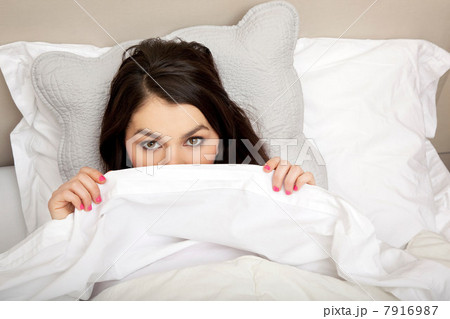 Woman peeking behind duvet Woman peeking behind duvet 7916987