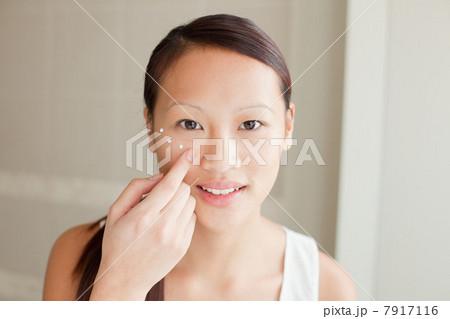 Woman applying moisturizer in bathroom Woman applying moisturizer in bathroom 7917116