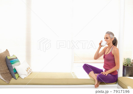 Woman sitting on window seat drinking herbal tea 7917196