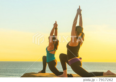 Women practicing yoga on rock formation 7917262