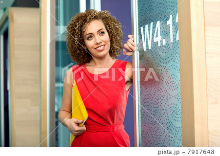 Young businesswoman holding file at doorway of office 7917648