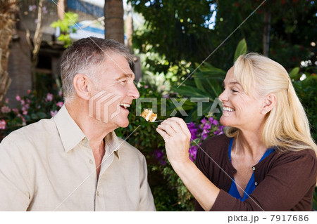 Mature woman feeding cake to husband 7917686