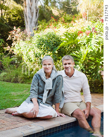 Couple sitting at poolside, portrait 7917743