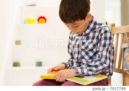 Young boy sitting on chair studying game Young boy sitting on chair studying game 7917789