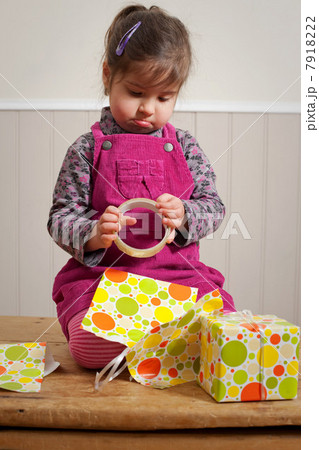 Little girl frowning as she wraps a gift Little girl frowning as she wraps a gift 7918222