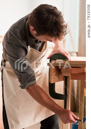 Carpenter adjusting clamp in workshop 7918306