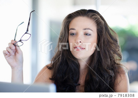 Woman holding glasses at desk 7918308