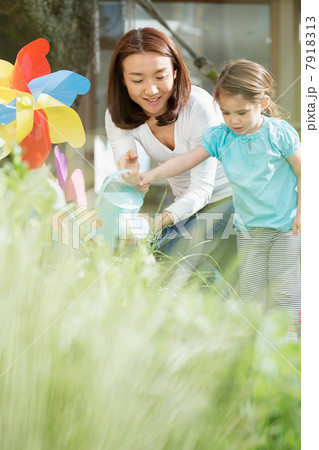 Mother and young daughter with watering can and toy windmill 7918313