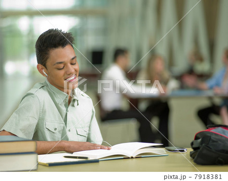 Young student wearing earphones and looking at school books 7918381