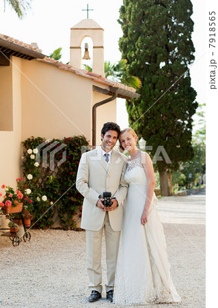 Portrait of newlyweds, groom holding vintage camera 7918565