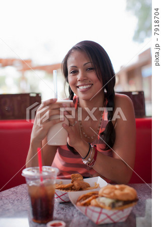 Young woman holding milkshake in diner, smiling Young woman holding milkshake in diner, smiling 7918704