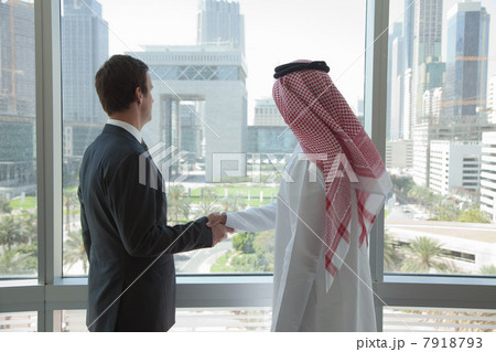 Western and middle eastern businessmen shaking hands by window 7918793