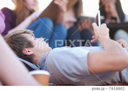 Young man lying down using smartphone Young man lying down using smartphone 7918902