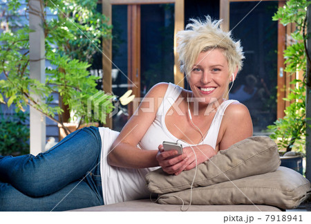 Young woman on sofa listening to music 7918941