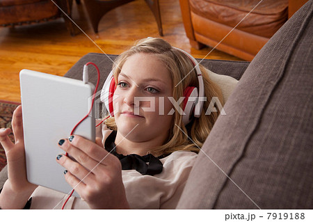 Girl lying on sofa using digital tablet 7919188