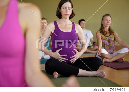 Pregnant woman in yoga class holding abdomen Pregnant woman in yoga class holding abdomen 7919401