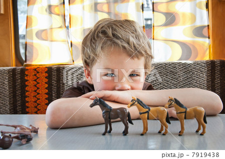 Boy playing with toy plastic horse in caravan 7919438