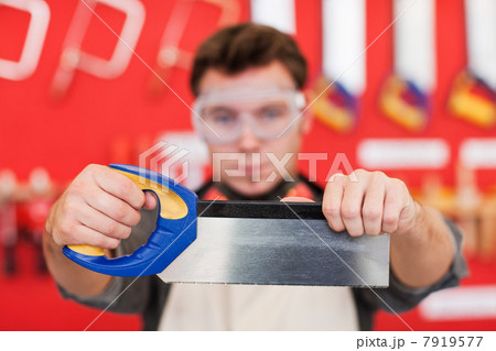 Carpenter holding saw in front of wood work tools 7919577