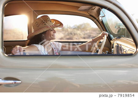 Young woman sitting in car on road trip, smiling 7919854