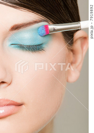 Young woman applying turquoise eyeshadow 7919892