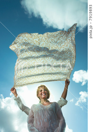 Person holding sarong in breeze over woman's head 7919893