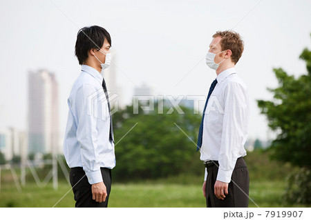 Two businessmen wearing pollution masks, face to face 7919907