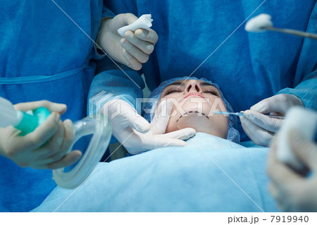 Young woman lying on operating table during facial plastic surgery Young woman lying on operating table during facial plastic surgery 7919940