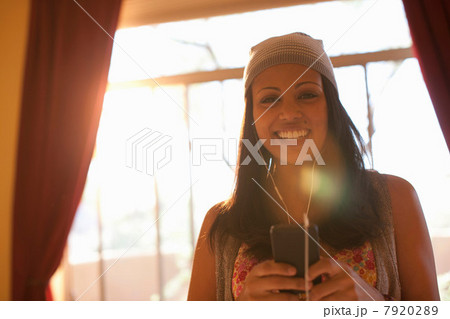 Young woman listening to mp3 player in hotel room, smiling 7920289