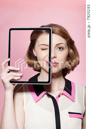 Woman covering half her face with digital tablet Woman covering half her face with digital tablet 7920293