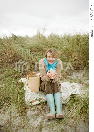Woman sitting on dune with hot drink 7920717