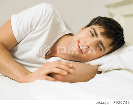 Young man lying on bed, portrait 7920739