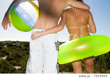 Young couple with inflatable ring and beach ball, rear view 7920909