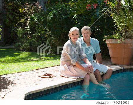 Couple sitting at poolside in garden Couple sitting at poolside in garden 7921005