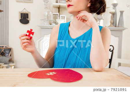 Woman doing heart shaped jigsaw puzzle holding piece Woman doing heart shaped jigsaw puzzle holding piece 7921091